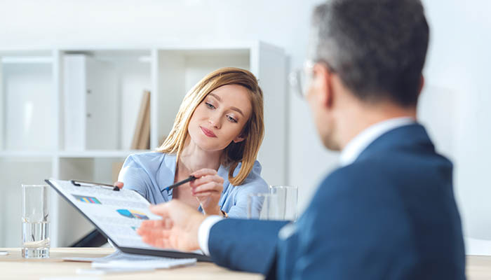 Personal growth coach reviewing charts and discussing progress with a client in a professional office setting, providing guidance and personalized support.